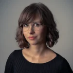 Kobieta w okularach z uśmiechem pozująca do portretu.