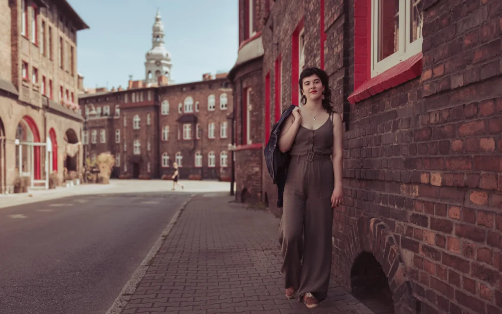 Kobieta przechadza się po mieście z kurtką przerzuconą przez ramię.