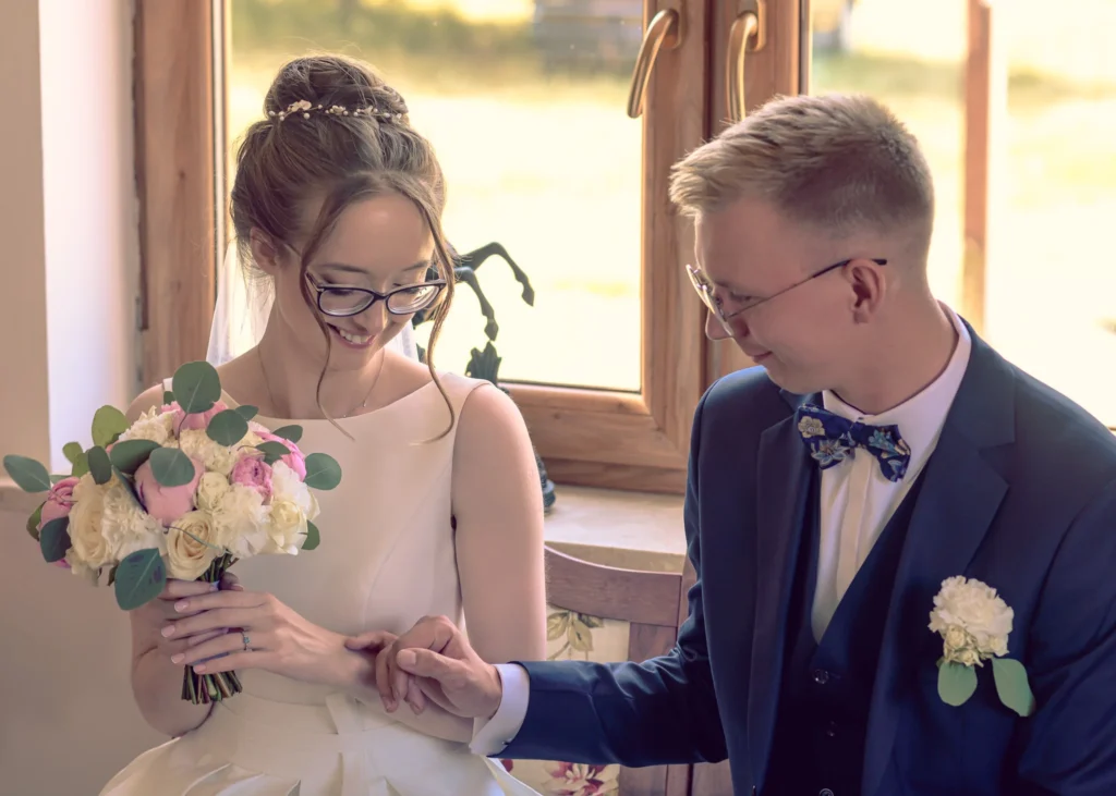 Uśmiechnięta para młoda trzymająca się za ręce przed ceremonią ślubną.