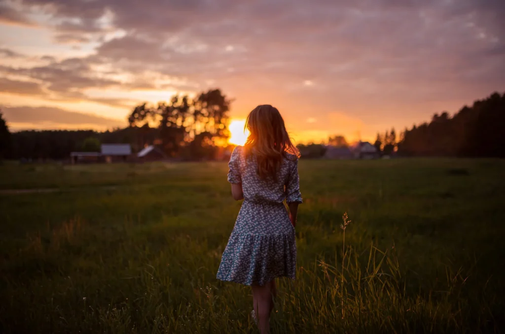 Klientka ciesząca się chwilą spokoju na łonie natury, z zamyślonym spojrzeniem w stronę zachodzącego słońca, podkreślającym jej zadowolenie i harmonię.
