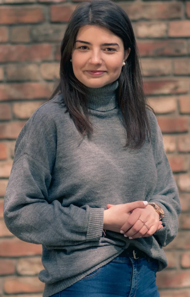 Młoda kobieta pozuje przed ceglaną ścianą.