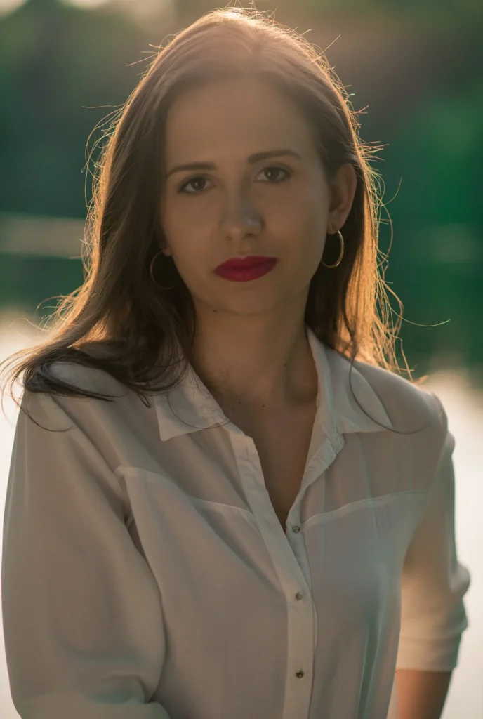 Portret kobiety nad jeziorem w ciepłym świetle zachodzącego słońca.