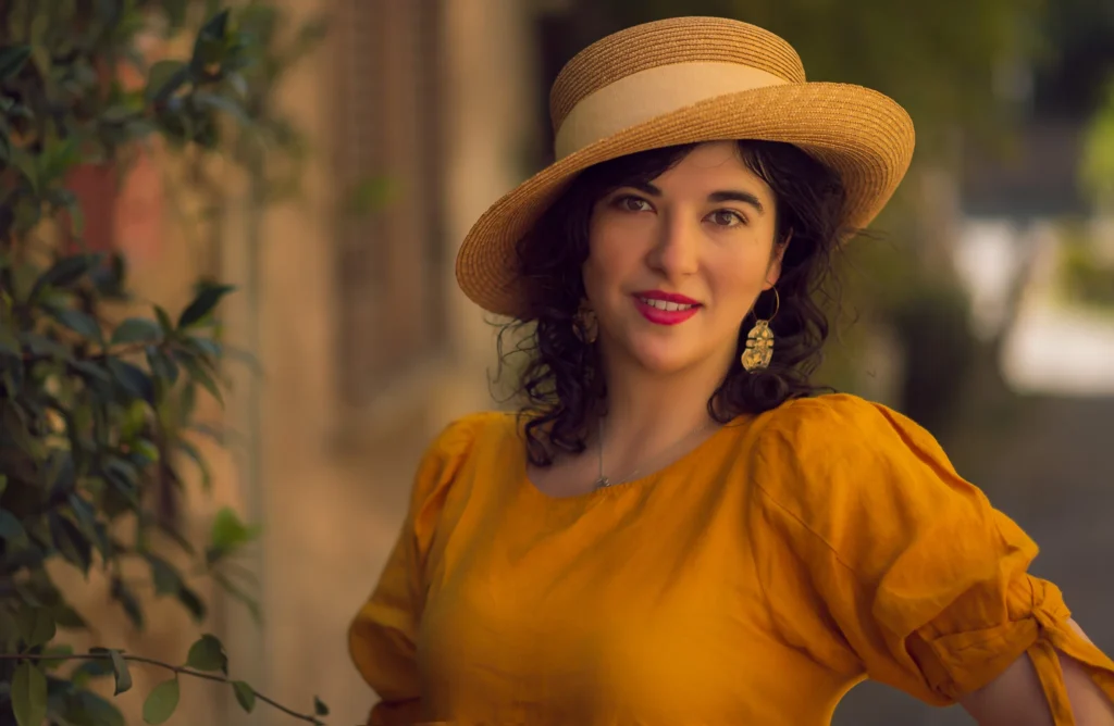 Kobieta w słomkowym kapeluszu i żółtej bluzce.