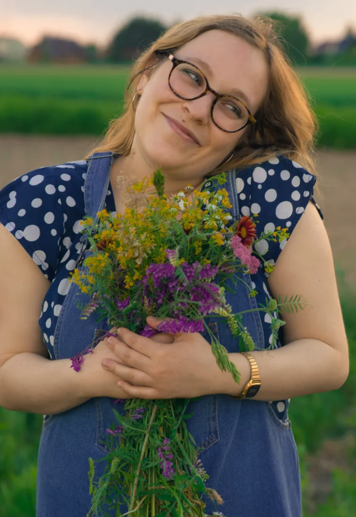 Uśmiechnięta kobieta trzymająca bukiet kwiatów.